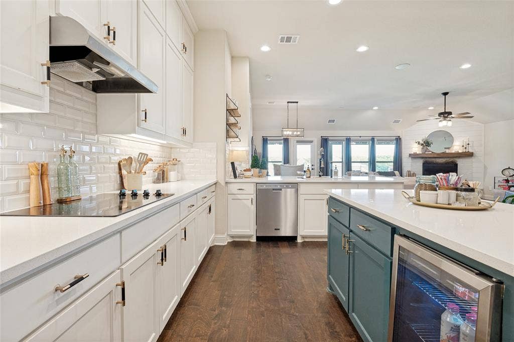 4601 Massey Meadows Way, Midlothian, TX 76065 Kitchen featuring white upper and lower cabinetry, white subway tile backsplash, dark wood-finish flooring, and a central island with a built-in beverage cooler