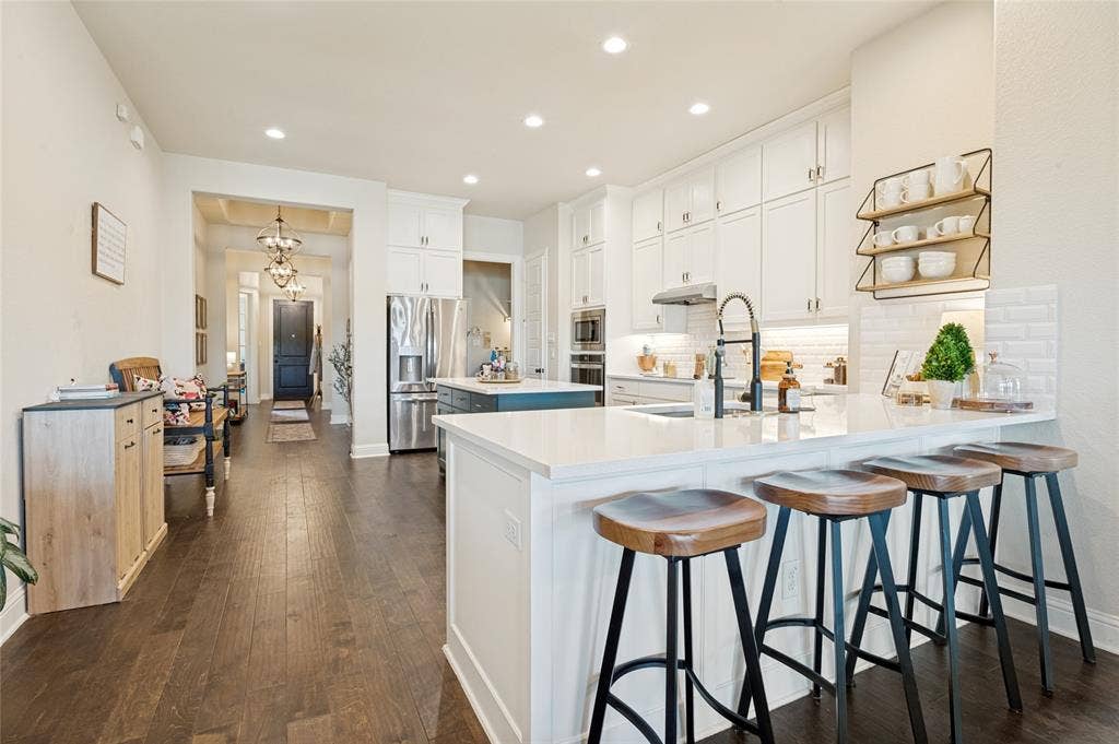 4601 Massey Meadows Way, Midlothian, TX 76065 Kitchen featuring white cabinetry, a large kitchen island with counter seating, stainless steel appliances, and wood-finish flooring