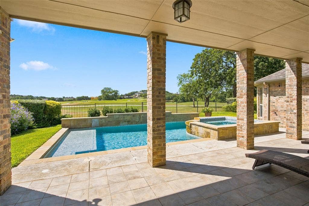 1820 Forest Bend Lane, Keller, TX 76248 Large covered patio overlooking 15th hole on the golf course with a stone tile surface, brick columns, swimming pool and spa.