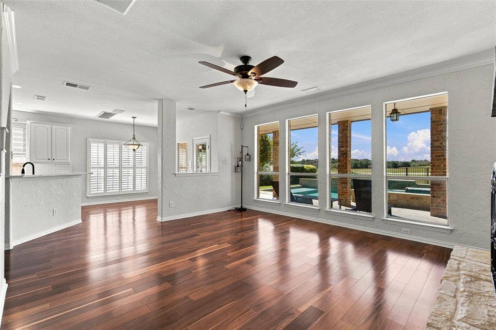 1820 Forest Bend Lane, Keller, TX 76248 Hardwood-finish flooring, ceiling fan, white cabinetry, built-in breakfast bar, and multiple large windows overlooking golf course and resort style backyard.