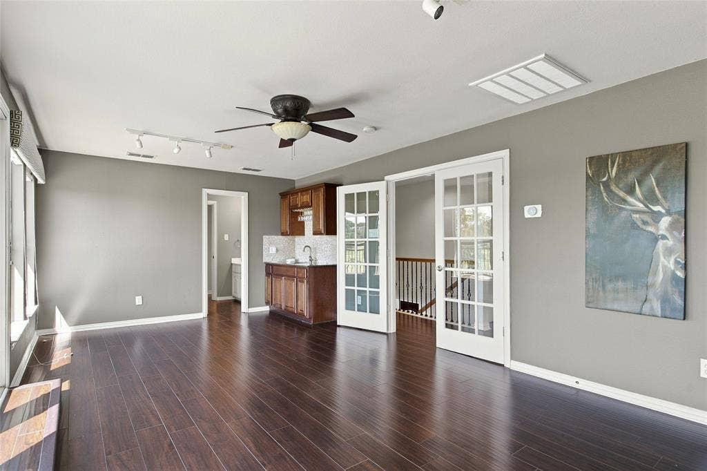 1820 Forest Bend Lane, Keller, TX 76248 Features ceiling fan with integrated lighting, built-in wet bar with cabinetry and tile backsplash, and white French doors with glass panels.