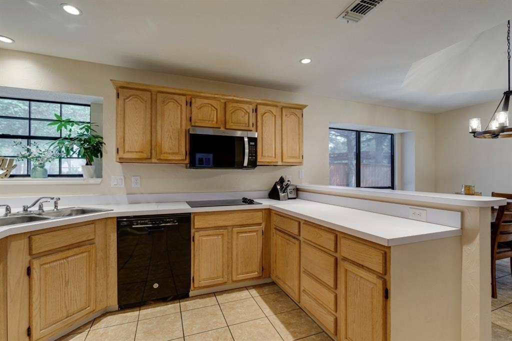 1408 Quapaw Trail, Mesquite, TX 75149 Wood-finish cabinetry with black appliances, light-toned countertops, and recessed lighting