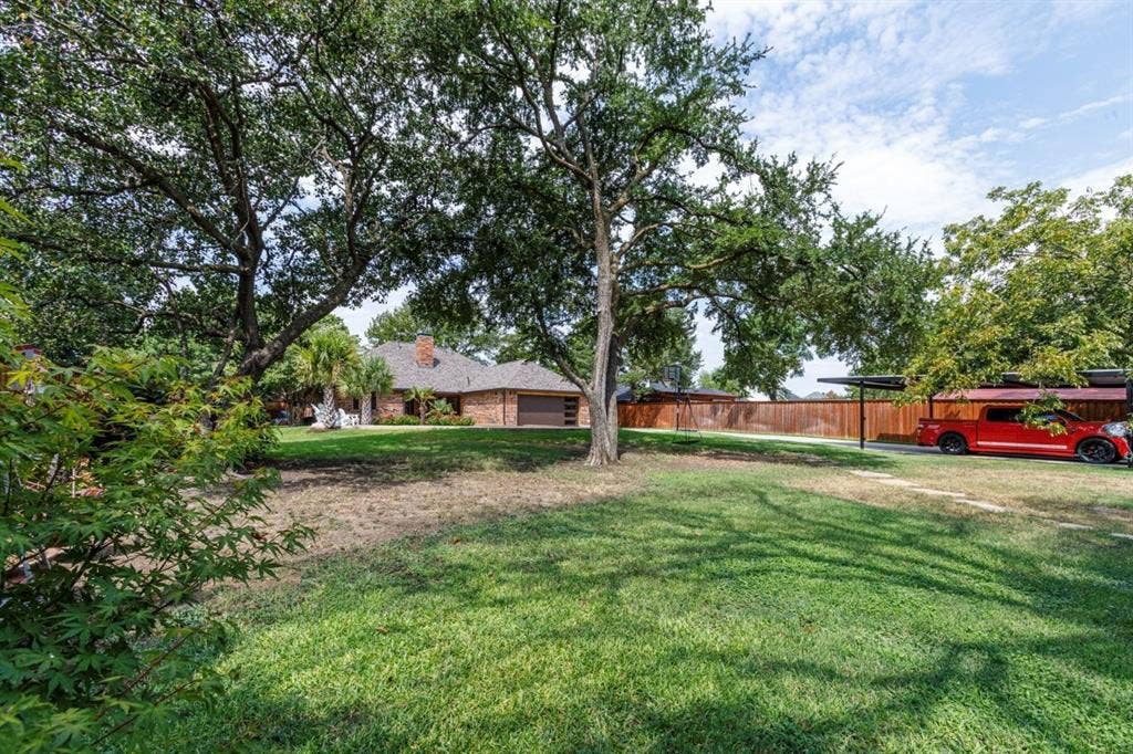 1408 Quapaw Trail, Mesquite, TX 75149 Expansive front yard featuring mature trees, a brick-front residence, and an attached two-car garage
