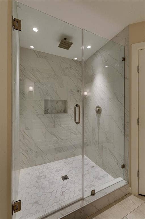 1408 Quapaw Trail, Mesquite, TX 75149 Glass-enclosed shower with a rainfall showerhead, tiled walls, hexagonal floor tiling, and an integrated shower niche