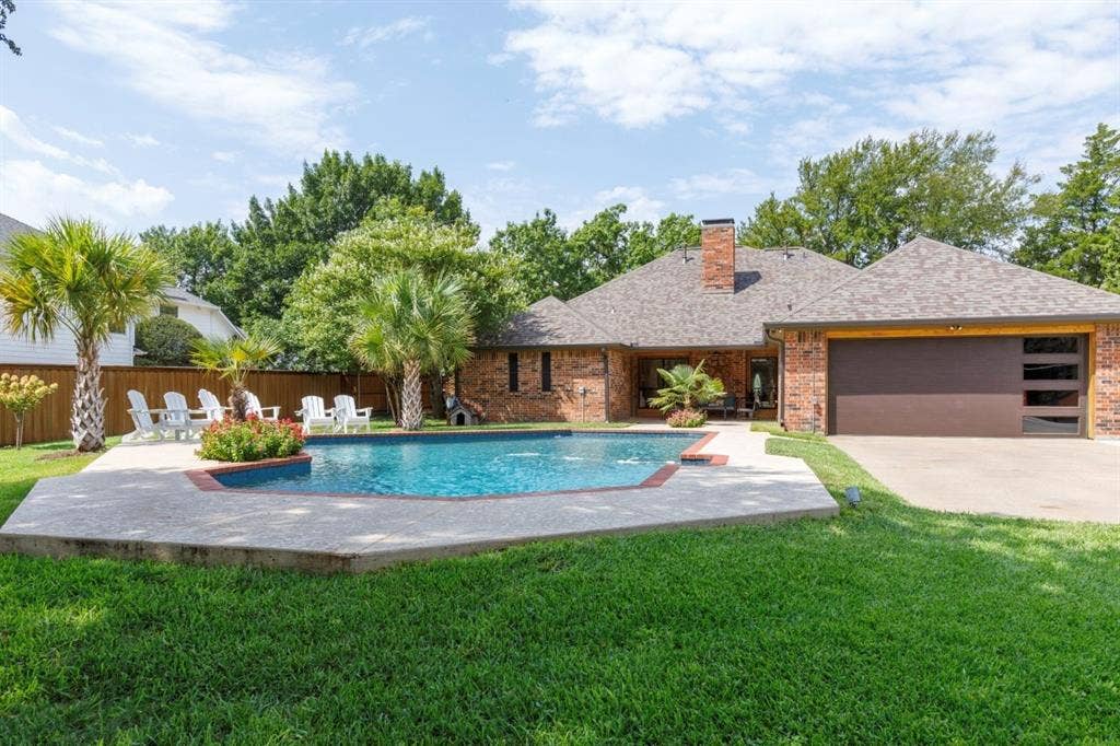 1408 Quapaw Trail, Mesquite, TX 75149 Brick exterior with a brown garage door featuring frosted glass panels, a full brick chimney, and a composite shingle roof