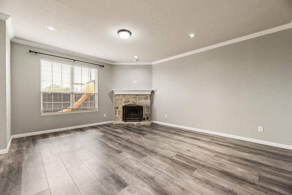 259 Saddlebrook Lane, Waxahachie, TX 75165 Spacious living room showcasing wood-finish flooring, recessed ceiling lighting, and large windows with plantation shutters