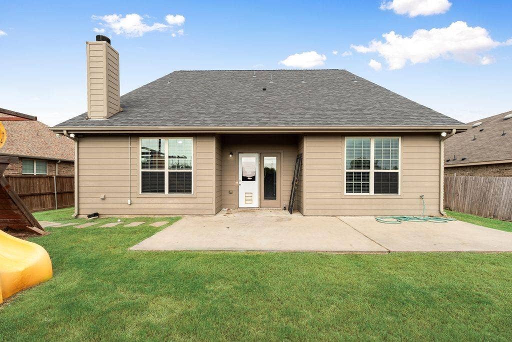 259 Saddlebrook Lane, Waxahachie, TX 75165 Charming single-story residence showcasing a spacious front facade with dual large windows, neutral exterior siding, a pitched gray roof, and a welcoming covered entry