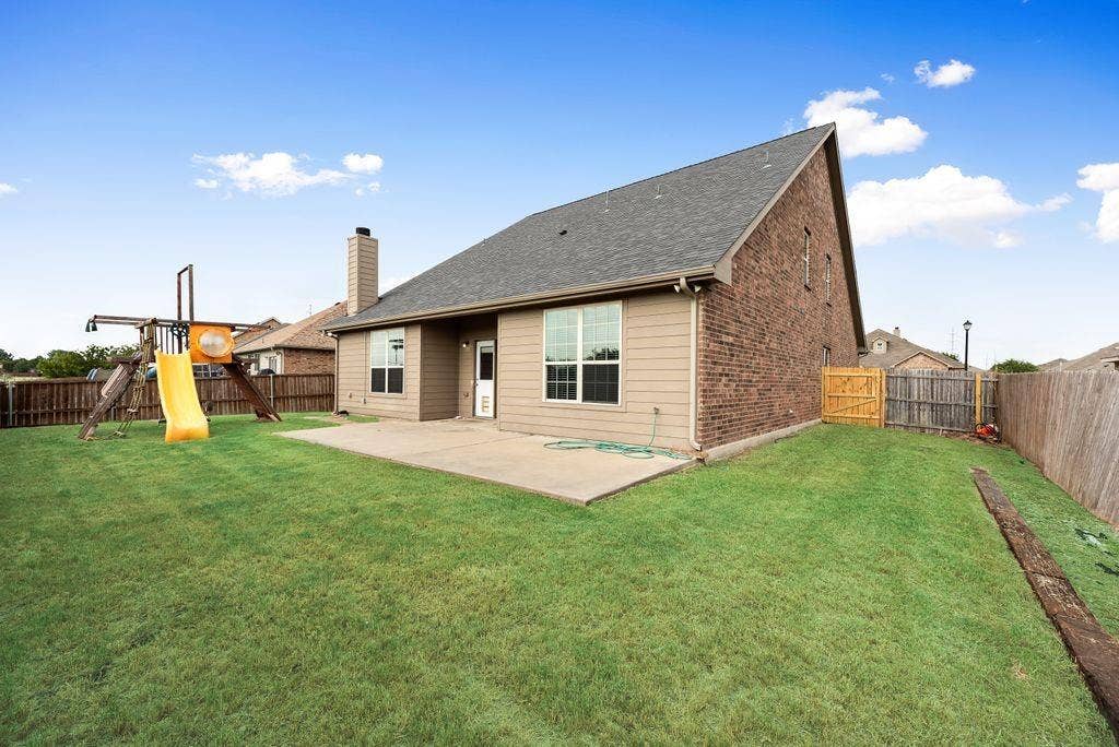 259 Saddlebrook Lane, Waxahachie, TX 75165 Expansive backyard with a manicured lawn, concrete patio, and privacy fencing