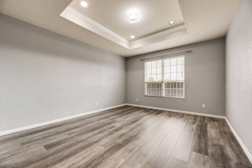 259 Saddlebrook Lane, Waxahachie, TX 75165 Spacious room featuring wood-finish flooring, recessed ceiling lighting with architectural detail, large window with grid-pattern glazing providing natural light, and neutral wall finishes throughout