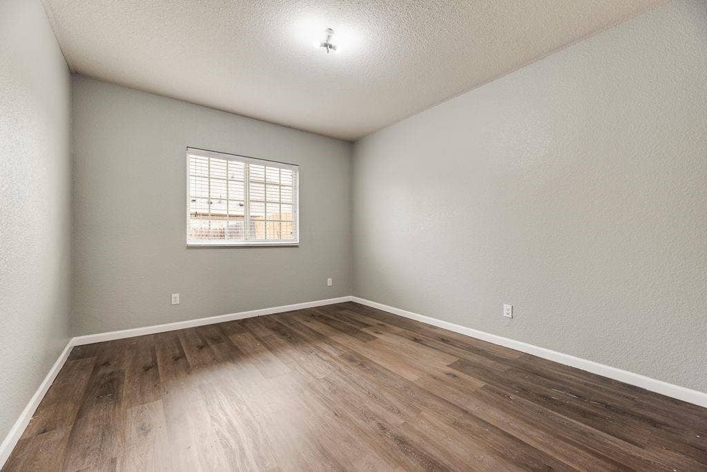259 Saddlebrook Lane, Waxahachie, TX 75165 Bright, neutral bedroom featuring wood-finish flooring, recessed ceiling lighting, and large window with security bars providing natural illumination