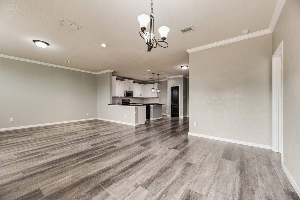 259 Saddlebrook Lane, Waxahachie, TX 75165 Spacious open-concept living area with wood-finish flooring throughout, recessed ceiling lighting, and a decorative pendant fixture