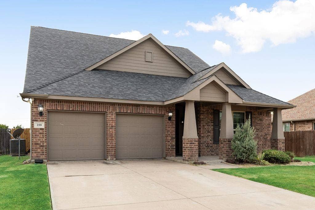 259 Saddlebrook Lane, Waxahachie, TX 75165 Brick exterior with a covered entry, two-car garage, and concrete driveway