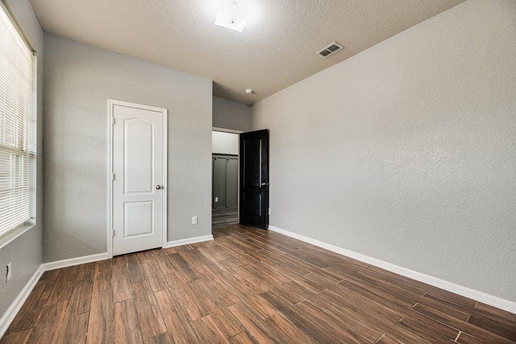 259 Saddlebrook Lane, Waxahachie, TX 75165 Bright, spacious bedroom featuring warm wood-finish flooring, clean white six-panel closet door, and recessed ceiling lighting