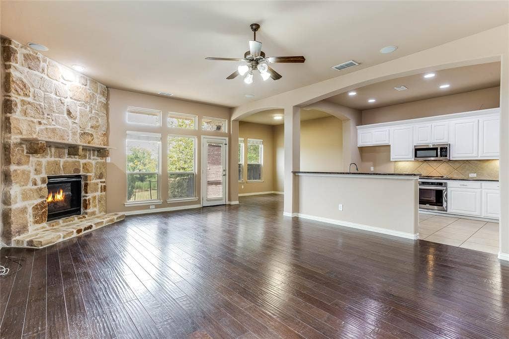 1014 Kaylie Street, Grand Prairie, TX 75052 Spacious living area featuring wood-finish flooring, a stone fireplace, and a ceiling fan