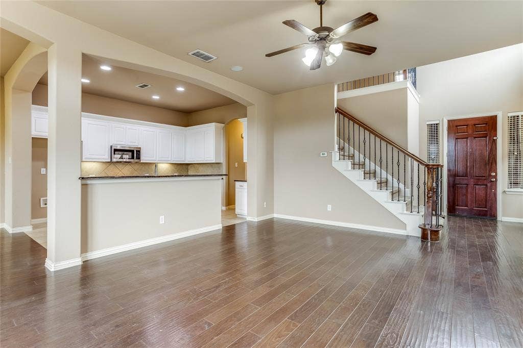 1014 Kaylie Street, Grand Prairie, TX 75052 Hardwood flooring, two-story ceiling, dark wood-paneled door, recessed lighting, and a staircase with decorative iron balusters