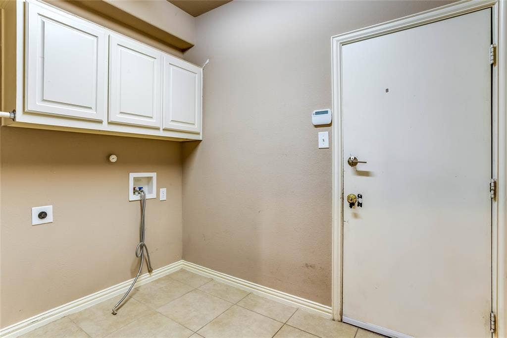 1014 Kaylie Street, Grand Prairie, TX 75052 White shaker-style cabinetry with overhead storage, tile flooring, and utility hookups