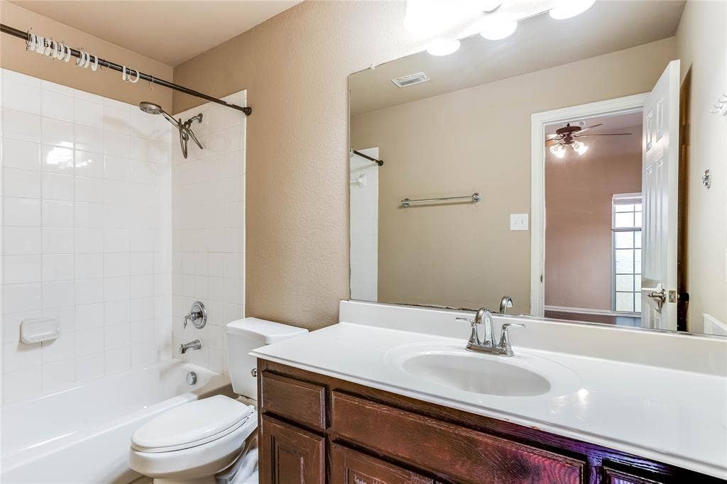 1014 Kaylie Street, Grand Prairie, TX 75052 White tile shower surround with a chrome shower head and faucet