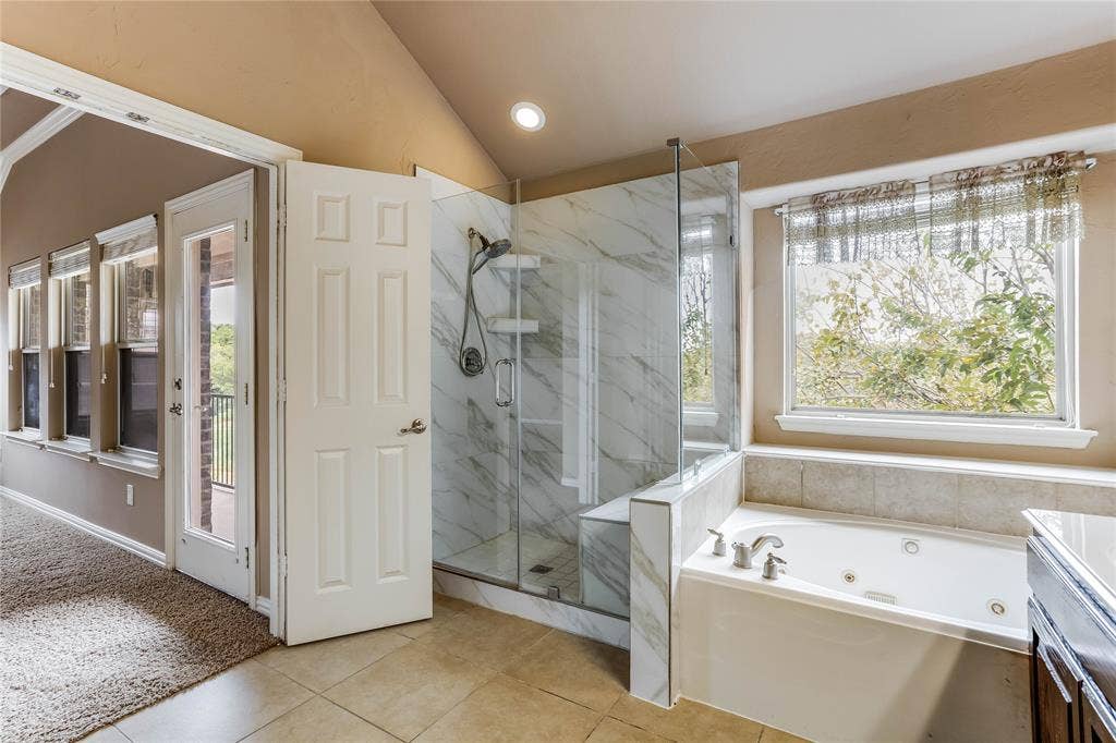 1014 Kaylie Street, Grand Prairie, TX 75052 Glass-enclosed shower with marble-finish tile, a built-in bench, and an adjacent jetted soaking tub