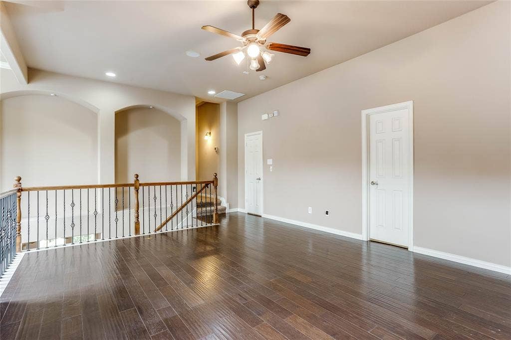 1014 Kaylie Street, Grand Prairie, TX 75052 Expansive room featuring wood-finish flooring, a ceiling fan with integrated lighting, recessed lighting, and a wrought iron and wood railing