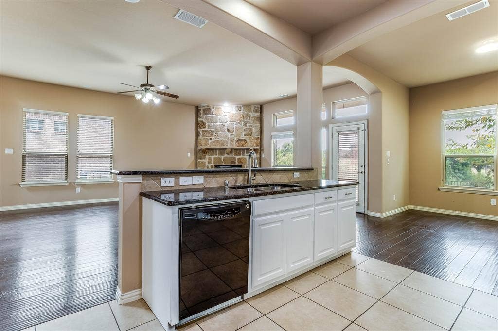 1014 Kaylie Street, Grand Prairie, TX 75052 Kitchen island with dark countertop, integrated sink, and white cabinetry