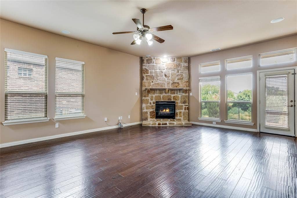 1014 Kaylie Street, Grand Prairie, TX 75052 Expansive living area with wood-finish flooring, a stone fireplace, and multiple windows