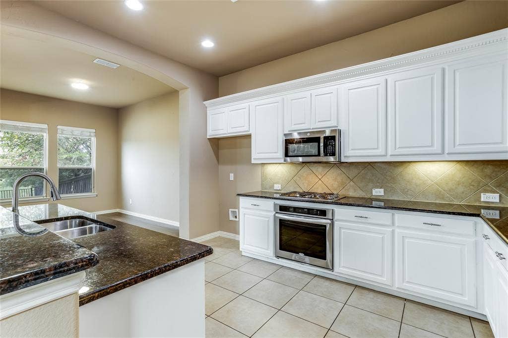 1014 Kaylie Street, Grand Prairie, TX 75052 Kitchen featuring white cabinetry, dark stone countertops, stainless steel appliances, tile flooring, and a tile backsplash
