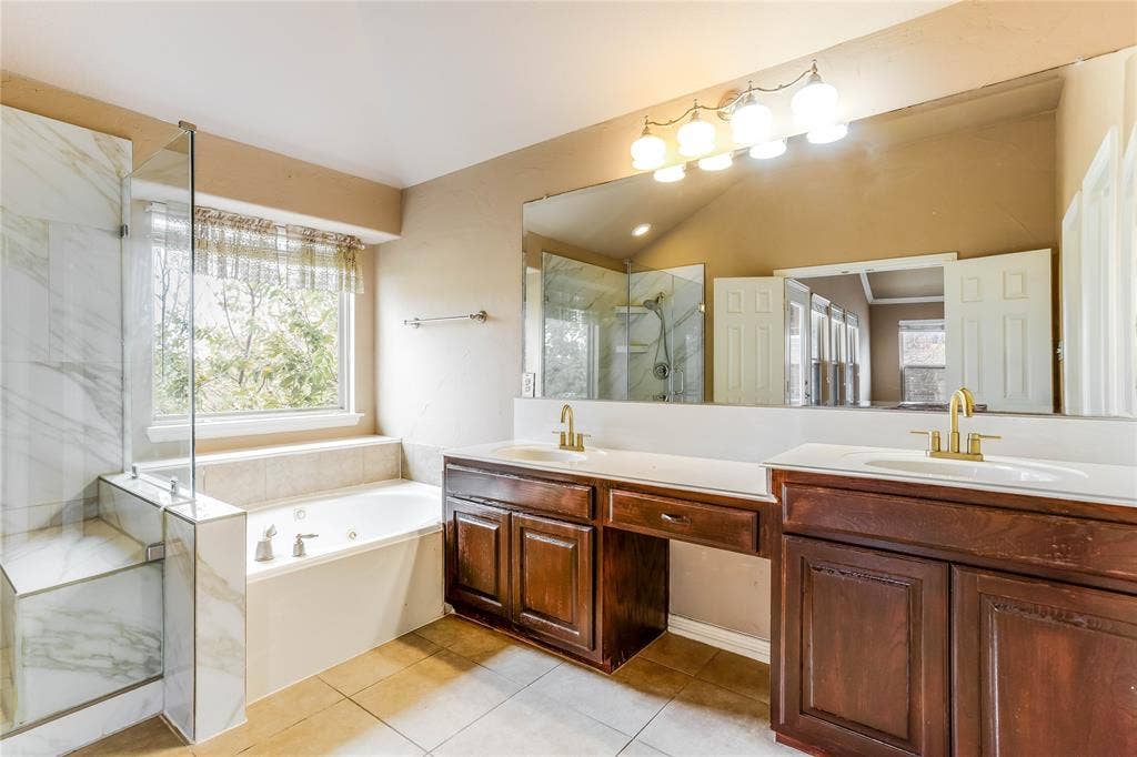 1014 Kaylie Street, Grand Prairie, TX 75052 Built-in soaking tub, separate glass-enclosed shower with tile surround, dual vanity with undermount sinks, and wood-finish cabinetry