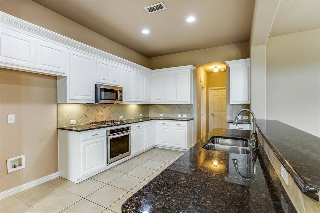 1014 Kaylie Street, Grand Prairie, TX 75052 Kitchen featuring white cabinetry, dark stone countertops, stainless steel appliances, and a tile backsplash