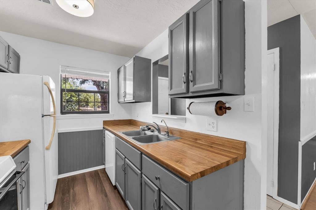 261 Oakview Circle, Waco, TX 76705 Kitchen featuring wood-finish countertops, grey cabinetry, stainless steel double-basin sink, and wood-finish flooring