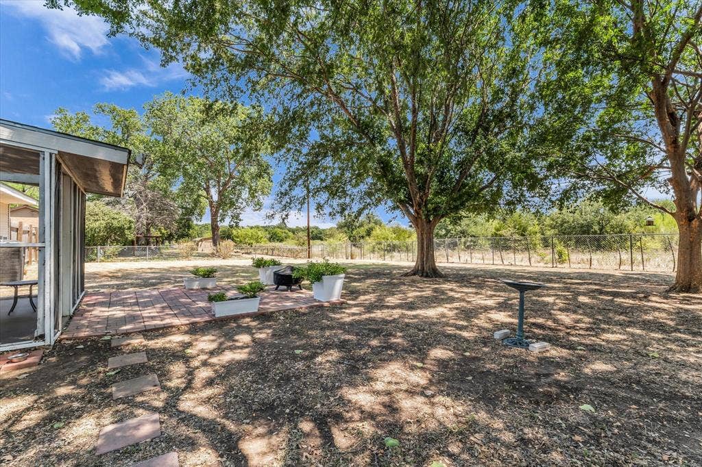 261 Oakview Circle, Waco, TX 76705 Expansive outdoor area featuring a screened-in porch, brick paver patio, and mature trees providing natural shade