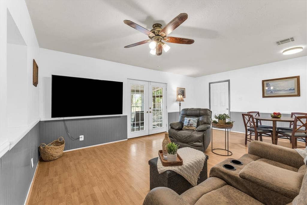 261 Oakview Circle, Waco, TX 76705 Spacious living area featuring wood-finish flooring, white walls with gray wainscoting, and a ceiling fan with integrated lighting