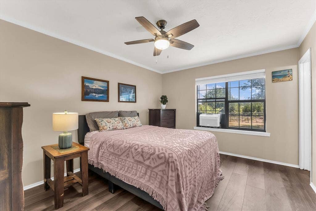 261 Oakview Circle, Waco, TX 76705 Wood-finish flooring, ceiling fan with integrated lighting, window with exterior scenery, crown molding, and neutral wall tones