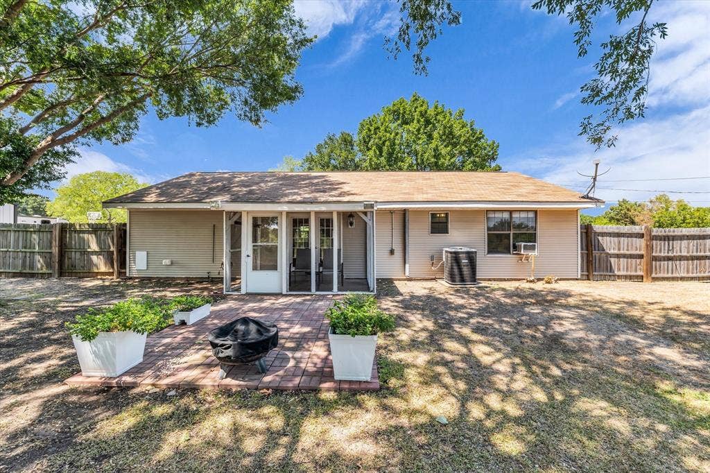 261 Oakview Circle, Waco, TX 76705 Rear exterior with a brick paver patio, screened porch entry, and wood privacy fencing