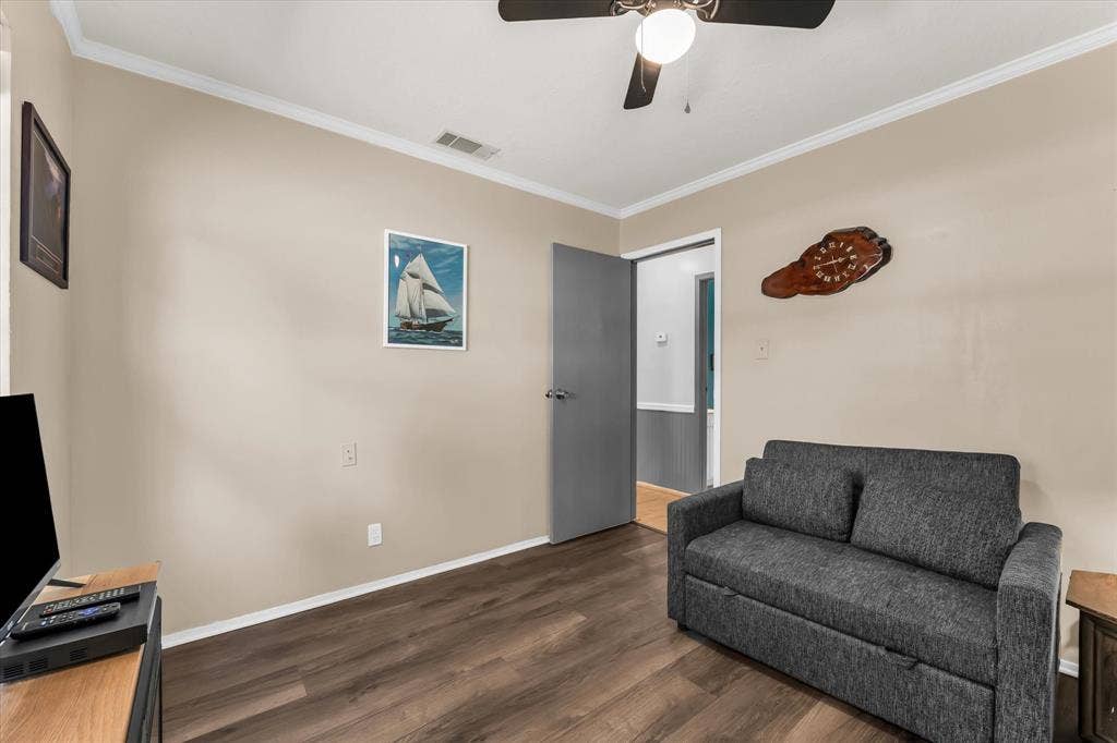 261 Oakview Circle, Waco, TX 76705 Wood-finish flooring, neutral wall paint, crown molding, and a ceiling fan with integrated lighting