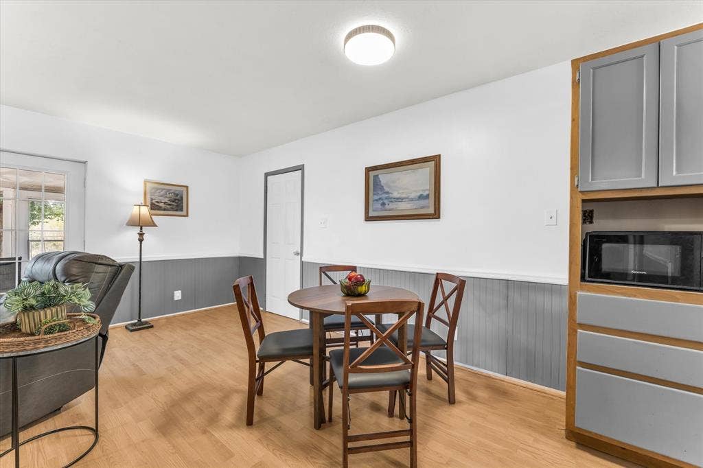261 Oakview Circle, Waco, TX 76705 Wood-finish flooring, built-in cabinetry with gray panel doors, integrated microwave, white walls, and wainscoting