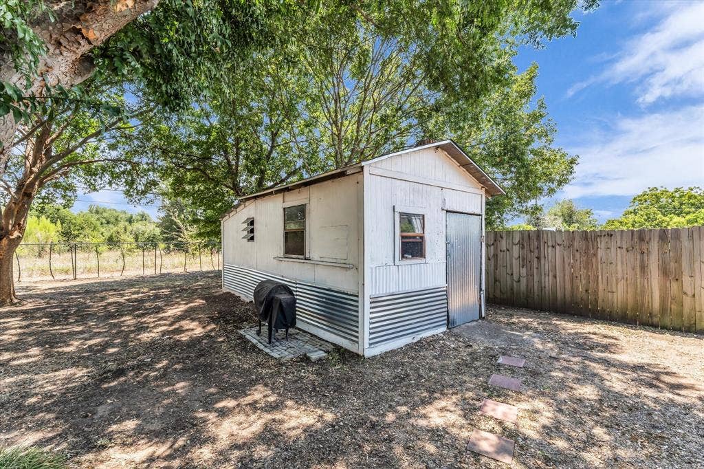 261 Oakview Circle, Waco, TX 76705 Storage shed with corrugated metal siding, wood-plank fencing, and mature trees