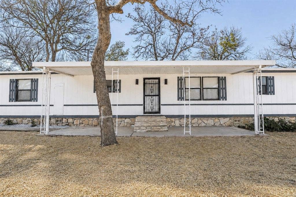 6048 Hidden Circle, Azle, TX 76020 White siding exterior with a dark grey stone foundation, covered front porch with white metal supports, and dark shutters
