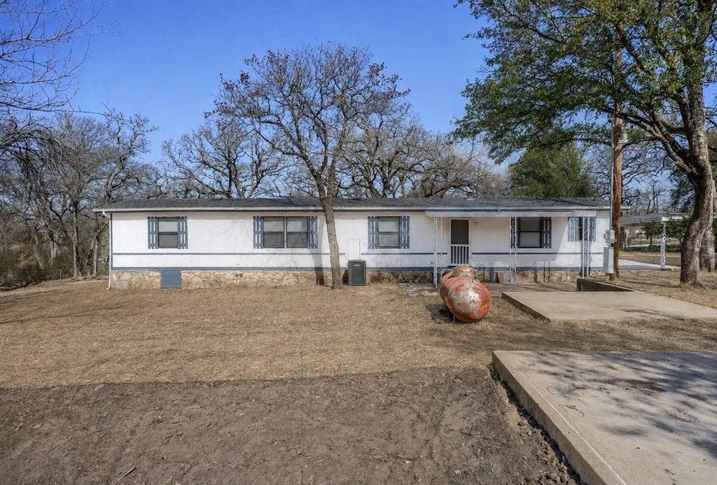 6048 Hidden Circle, Azle, TX 76020 Single-story residence featuring a white exterior with blue trim, a stone-finish foundation, and multiple windows
