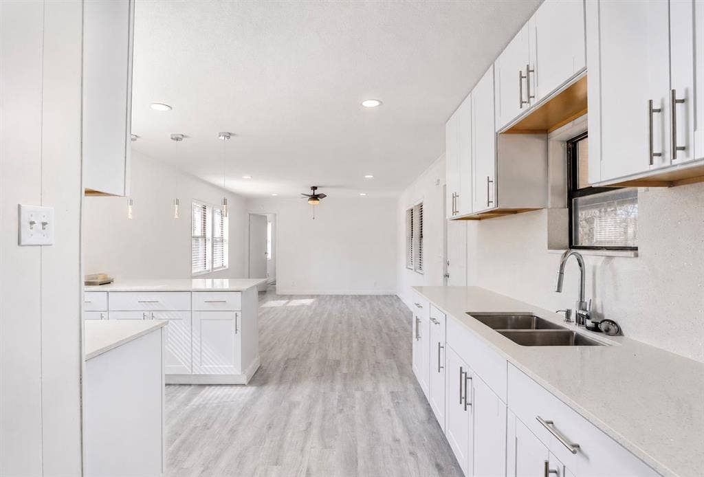 6048 Hidden Circle, Azle, TX 76020 Kitchen featuring white shaker cabinetry, light-toned countertops, stainless steel double-basin sink with a gooseneck faucet, and recessed lighting
