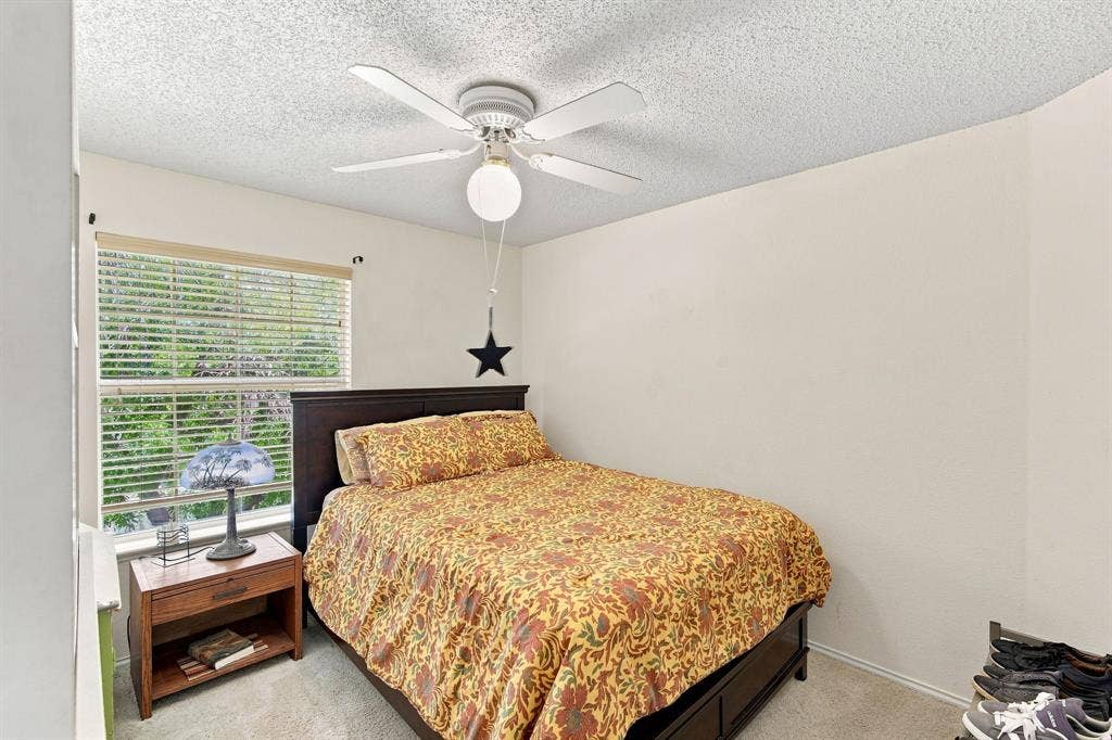 Carpeted bedroom with a window featuring blinds, a ceiling fan with integrated lighting, and neutral wall tones