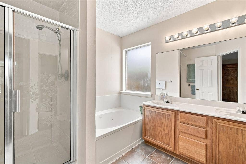 Dual vanity with integrated sinks, wood-finish cabinetry, a full-width mirror, and a multi-bulb light fixture