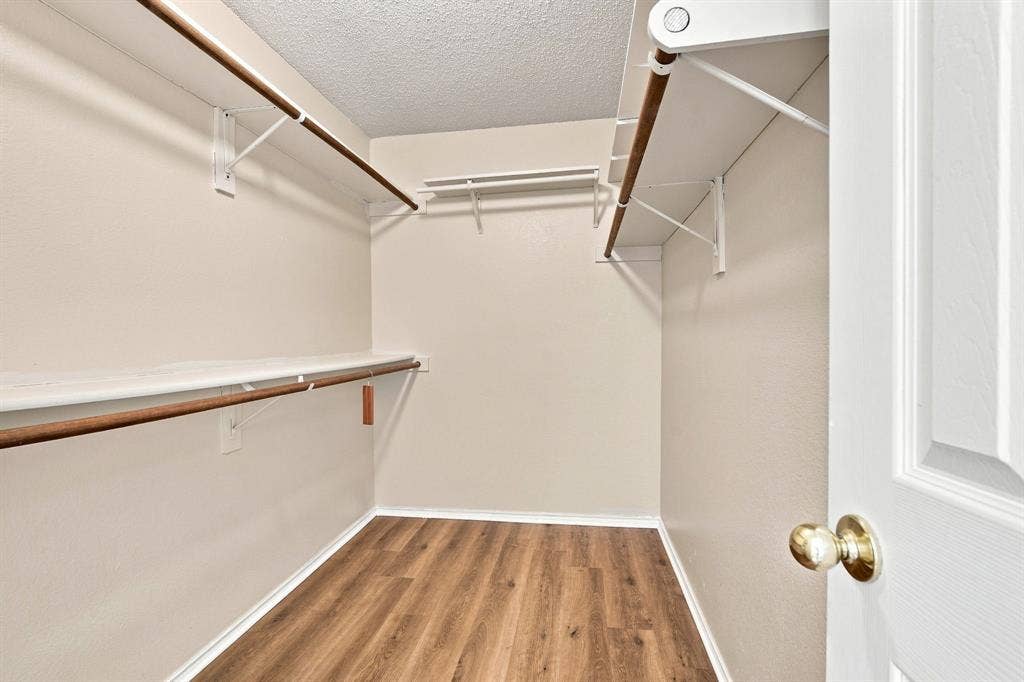 Walk-in closet featuring wood-finish flooring, multiple shelving units, and clothing rods
