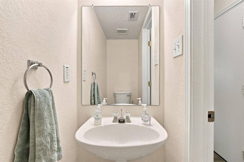 Wall-mounted sink with a single-handle chrome faucet and a rectangular mirror
