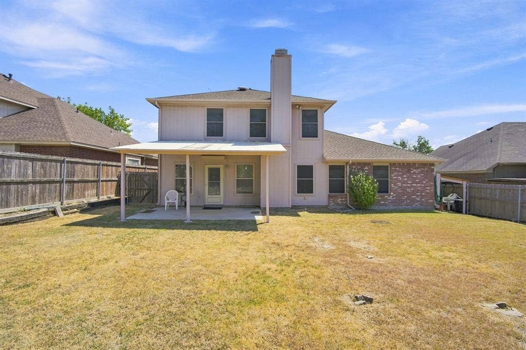 Private backyard with a covered patio, wood fencing, and a brick and siding exterior