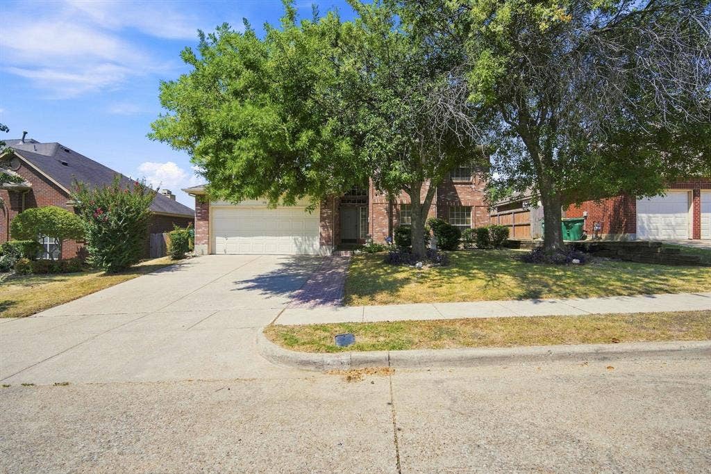 Brick exterior, attached garage, concrete driveway, mature trees, landscaped front yard
