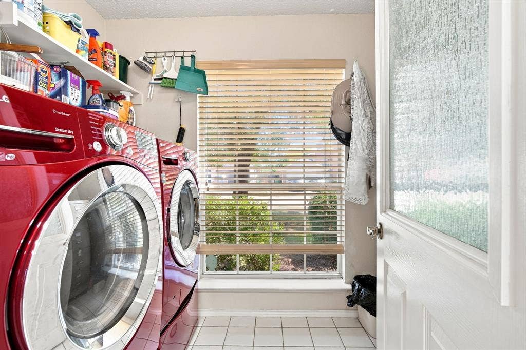 White tile flooring, a window with blinds, and white shelving provide functional storage
