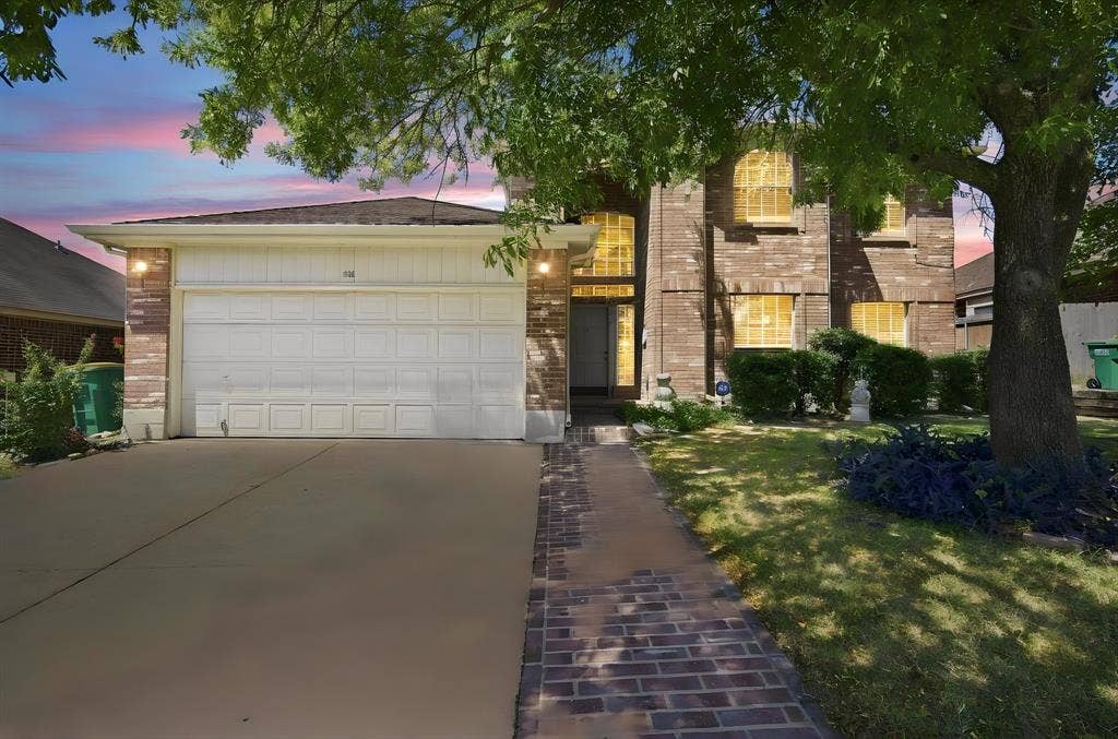 Brick facade with arched windows, attached garage, and a brick-finish walkway
