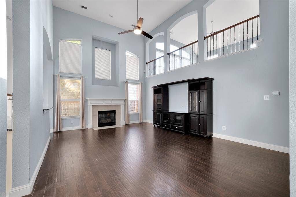 2106 Hillside Drive, Rowlett, TX 75088 Spacious living room featuring soaring ceilings, abundant natural light, a cozy fireplace, and an open second-story overlook.