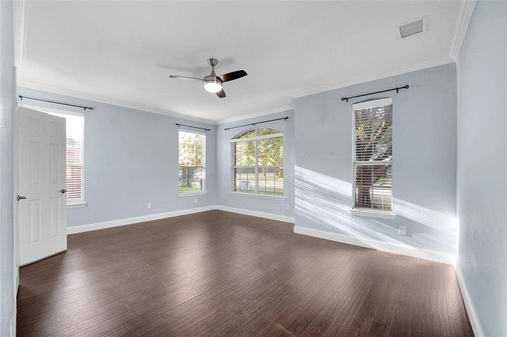 2106 Hillside Drive, Rowlett, TX 75088 Spacious primary suite featuring abundant natural light, wood-look flooring, a ceiling fan, and plenty of room to create a relaxing retreat.
