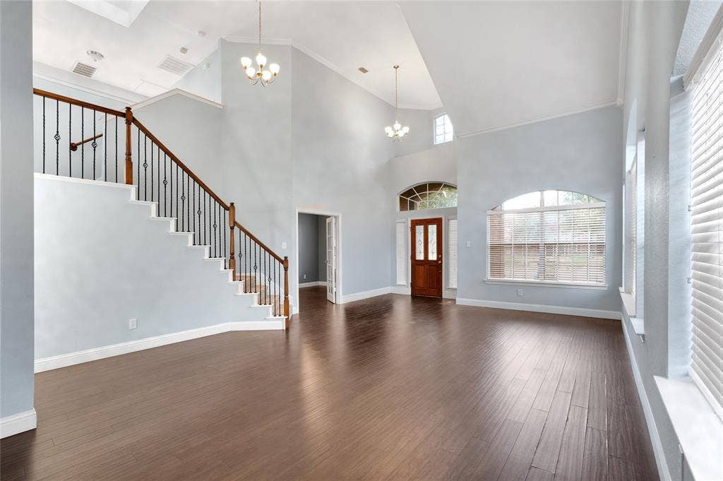 2106 Hillside Drive, Rowlett, TX 75088 Bright, open entryway featuring soaring ceilings, rich wood-look flooring, a grand staircase, and abundant natural light.